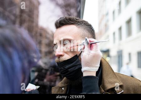 Close-up of an unrecognizable makeup artist putting makeup on a hipster man's face Stock Photo