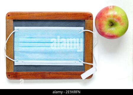 School lockdown during corona pandemic, blackboard, protective mask and apple, back to school concept Stock Photo