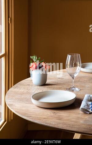 Served table with ceramic plates with cutlery on napkin near wineglasses and flowers with fruits Stock Photo