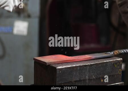 Red hot metal product on heavy anvil for forging and changing form in blacksmith workshop Stock Photo