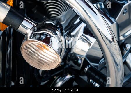 The headlight of a powerful road bike with a shiny chrome reflective surface of the engine in the street parking lot, close-up with a small depth of f Stock Photo