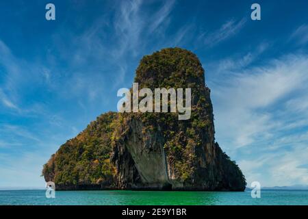 A giant rock formation overshadows the blue sea at Railay Beach in Krabi, Thailand Stock Photo