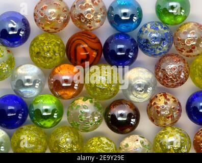 Photo of Glass marbles with patterns and solid colours reflecting light close up