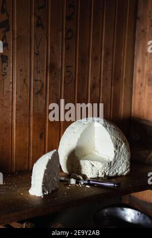 Still life with farmer cheese and a knife on rustic wooden background. Stock Photo