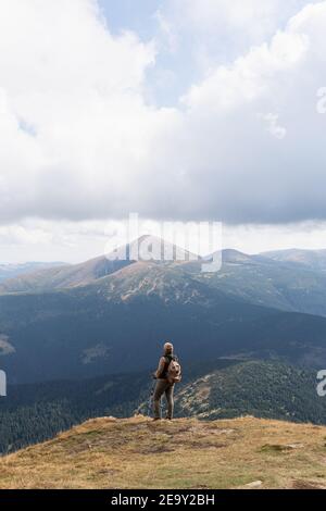 Woman hiking with backpack and trekking poles on summer day. Nature tourism in Ukrainian Carpathian mountains. Stock Photo