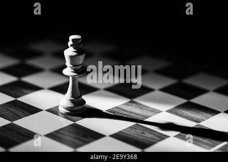 White single king Chess piece with shadow against a black background. Black and White photo. Stock Photo