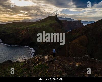Hiker standing in front of stunning cliffs and a stunning landscape of Madeira at Ponta de Sao Lourenco - Green mountain landscape Stock Photo