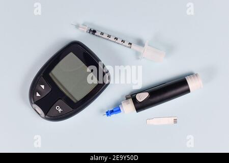 Equipment for diabetes treatment with blood glucose sugar meter, lancet, syringe and lancing device on blue background Stock Photo