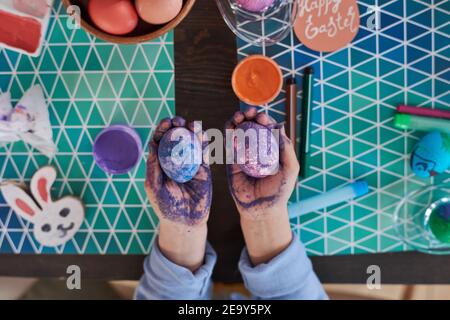 High angle view of child holding painted eggs in her hands she coloring them with special technique Stock Photo