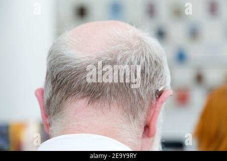 Head of an old man with a deaf aid. Close-up from the back. Stock Photo