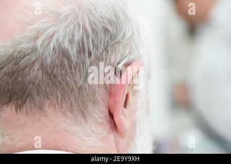 Head of an old man with a deaf aid. Close-up from the back. Stock Photo