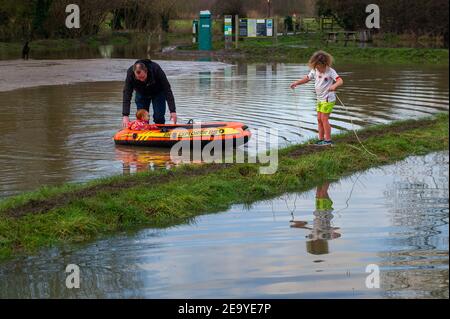 Cookham, Berkshire, UK. 6th February, 2021. A family having fun in the floodwater. A Flood Alert remains in force along the stretch of the River Thames from Hurley to Cookham. The Pound across Cookham Moor flooded earlier this week and remains closed to traffic following flooding. The flood water levels have lessened, however, further rain is expected overnight together with possible snow and the Environment Agency are closely monitoring the situation. Credit: Maureen McLean/Alamy Live News Stock Photo