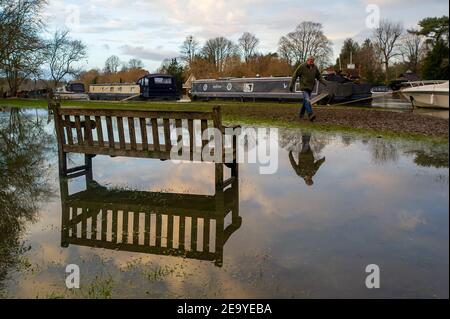 Cookham, Berkshire, UK. 6th February, 2021. A man walks along a muddy tow path in Cookham. A Flood Alert remains in force along the stretch of the River Thames from Hurley to Cookham. The Pound across Cookham Moor flooded earlier this week and remains closed to traffic following flooding. The flood water levels have lessened, however, further rain is expected overnight together with possible snow and the Environment Agency are closely monitoring the situation. Credit: Maureen McLean/Alamy Live News Stock Photo