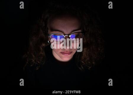 Computer screen reflected in the glasses of a woman who works at night. Overwork concept. Stock Photo