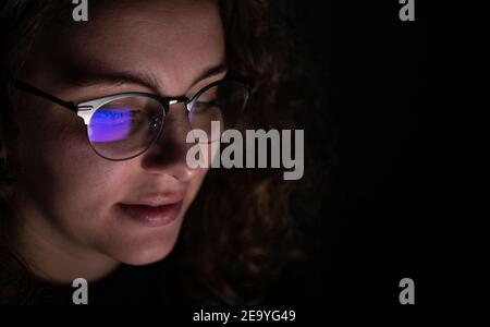 Computer screen reflected in the glasses of a woman who works at night. Overwork concept. Stock Photo