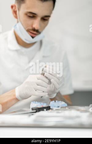 Dental technician working with a model of teeth and dental braces Stock Photo