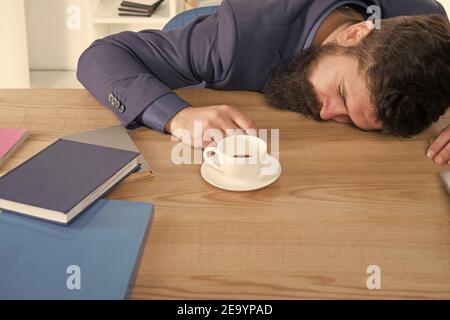 Tired businessman sleep in office. boss fell asleep on table. Man sleeping over workplace. coffee will help me. bored and exhausted guy sleep at work. need break for relax. being lazy. Stock Photo