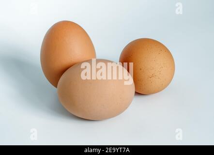 three brown chicken eggs on a light background Stock Photo