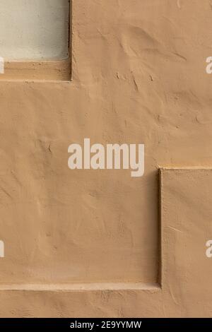 Vertical close-up image of a beige stucco wall, with small indentation at top left and an L-shaped shelf at lower right, useful image for copy space. Stock Photo