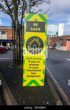 Sign with instructions to self-isolate if anyone has symptoms in Woking town centre, Surrey, south-east England during COVID-19 lockdown Stock Photo