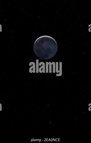 Waxing crescent moon with a night sky stars background. Amazing view of the tiny moon surface illuminated by the sun and the dark side of the moon. Dr Stock Photo