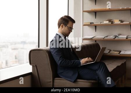 Young man visitor sitting on sofa in office using pc Stock Photo