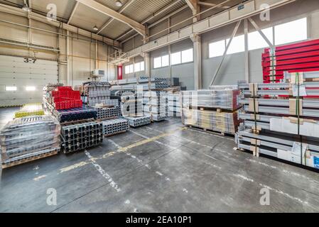 Finished goods warehouse, metal profile packed in bundles. Metal packages are on high storage racks. Large storage room. Stock Photo