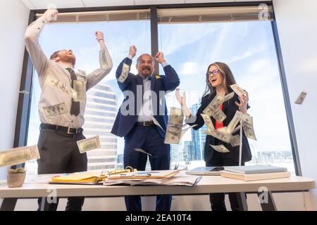 Employees celebrating business success with paper money Stock Photo