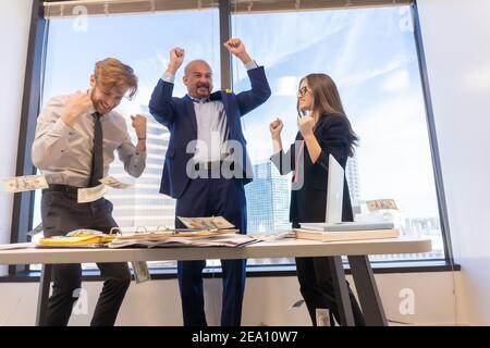 Employees celebrating business success with paper money Stock Photo