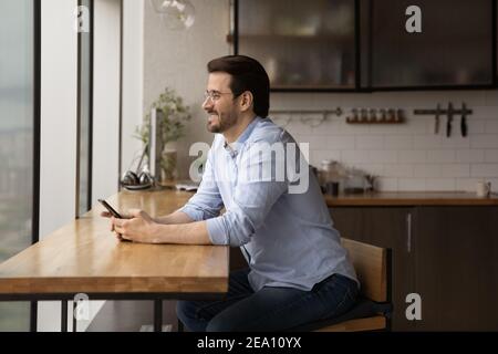 Happy young man pondering on phone message from beloved woman Stock Photo