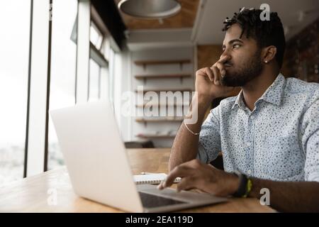 Young afro guy think before typing correct answer on pc Stock Photo