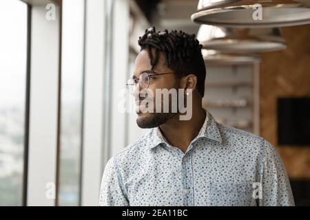 Confident young african man looking at window thinking happy thoughts Stock Photo
