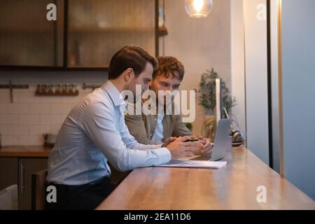 Young man analyse electronic report mistakes with skilled male colleague Stock Photo