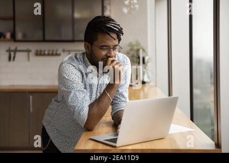 Smiling black guy freelancer read good message on laptop screen Stock Photo