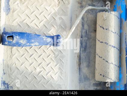 Roller in white paint in a container  Stock Photo