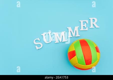 Bright multi-colored volleyball ball and tex Summer from white volume letters on blue background. Top view Flat lay Minimal style Template for card, d Stock Photo
