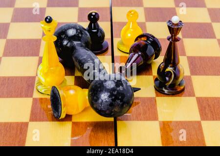 Dumbbell lies on a chessboard, on white chess king, black have fallen nearby. Victory of power over the mind. Stock Photo