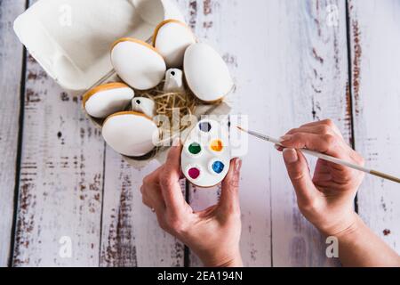 Hand decorating gingerbread colorful cookies on wooden background. Top View. Easter cookies. Stock Photo