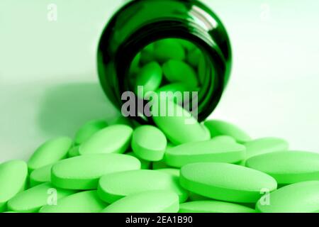 Bright Lime green pills poured from dark green glass bottle on the table Stock Photo
