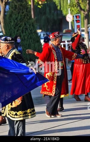 ,Zhangye, China-October 20, 2017: Early morning-group of elderly dancers dressed in Uyghur clothing perform traditional choreographies to the sound of Stock Photo
