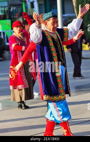 Zhangye, China-October 20, 2017: Early morning-group of elderly dancers dressed in Uyghur clothing perform traditional choreographies to the sound of Stock Photo