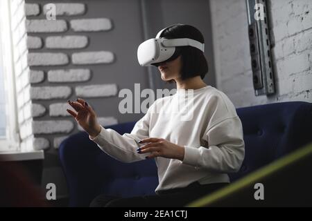 team of four creative engineers working with virtual reality, young woman testing VR glasses or goggles sitting in the office room Stock Photo