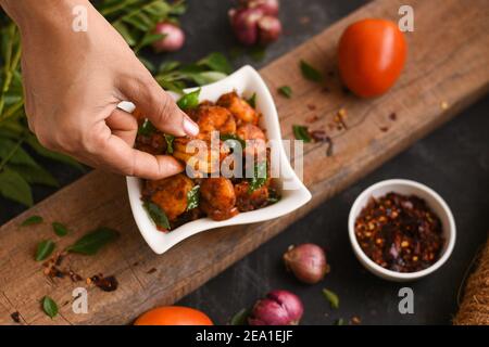 Top view spicy hot Bengali Prawn roast , shrimp masala fish curry. Indian food. Woman hand take Fish fry red chili, curry leaf. Asian cuisine, Kerala, Stock Photo