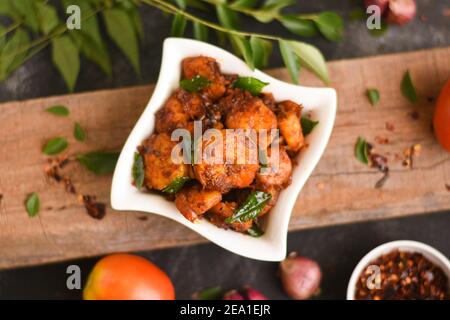 Top view spicy hot Bengali Prawn roast , shrimp masala fish curry. Indian food. Woman hand take Fish fry red chili, curry leaf. Asian cuisine, Kerala, Stock Photo