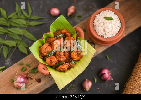 Top view spicy hot Bengali Prawn roast , shrimp masala fish curry. Indian food. Woman hand take Fish fry red chili, curry leaf. Asian cuisine, Kerala, Stock Photo