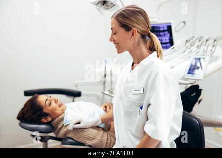 Dentist preparing female patient for treatment in clinic. Dental doctor with female patient in hospital. Stock Photo