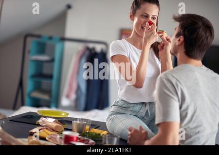 A young couple playing during a breakfast in a cheerful atmosphere at home. Couple, love, breakfast, together Stock Photo