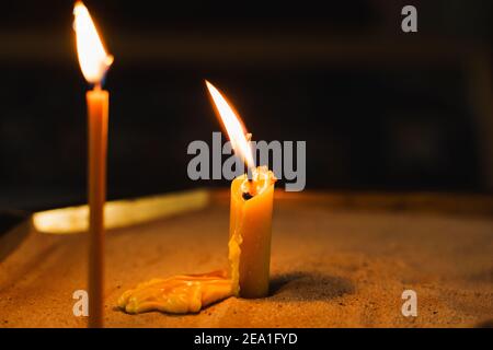 Burning candles close-up on dark background in church. Tragedy. Orthodox tradition and faith. Equipment for praying. Pray for people life. Pray to god Stock Photo