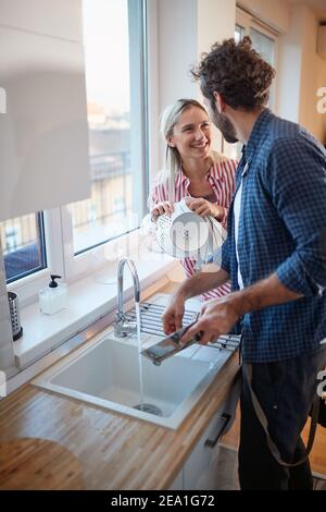 A happy young couple in love doing housework in a relaxed atmosphere together. Kitchen, housework, home, relationship Stock Photo