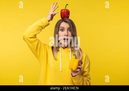 Photo of attractive lady holds papers and one of its on head, surprised face. Wears casual yellow hoody, isolated yellow color background Stock Photo